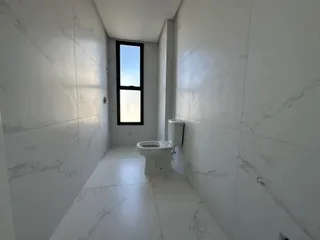 Foto de um banheiro com paredes de revestimento em mármore branco e janela.