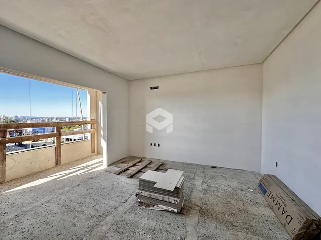 Interior de uma sala em construção com piso de concreto e vista para o exterior.