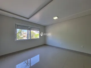Sala de estar ampla com piso claro e grande janela.