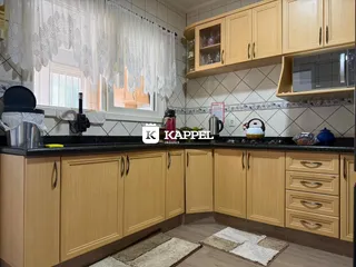 Cozinha com armários de madeira clara e bancadas escuras.