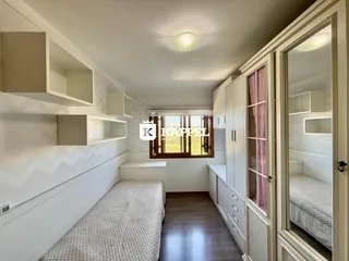 Quarto com cama e armários em um ambiente claro com piso de madeira.