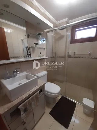 Banheiro com box de vidro e revestimento claro.