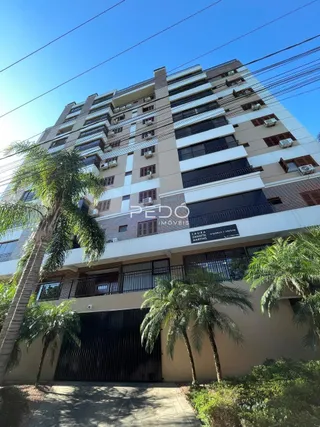 Fachada de um prédio residencial em Lajeado, Brasil, com varandas e vegetação.