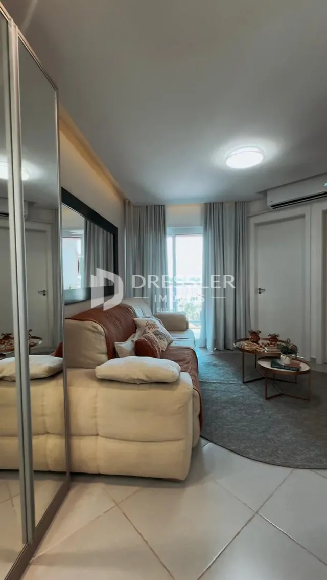 Sala de estar com sofá e cortinas claras.