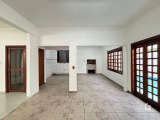 Ambiente interno de uma sala ampla com piso de cerâmica e parede branca.
