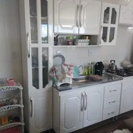 Cozinha com armários brancos e bancadas em um imóvel.