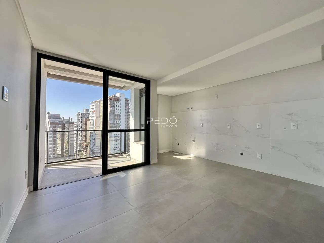 Sala de estar ampla com vista para o horizonte da cidade através de portas de vidro.