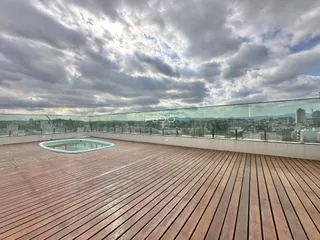 Vista panorâmica de uma área externa com deck de madeira e vista da cidade.