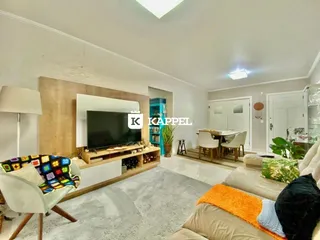 A sala de estar apresenta um sofá e uma televisão montada na parede.