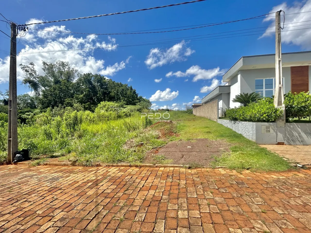 Vista externa da propriedade com jardim e pátio de tijolos.