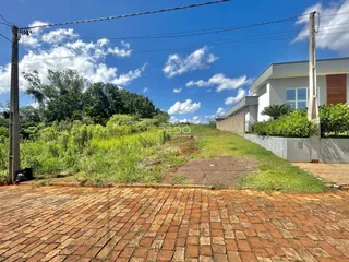Vista externa da propriedade com jardim e pátio de tijolos.