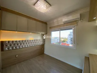 Quarto com cabeceira estofada e armários em madeira clara.