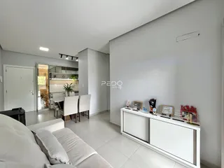 Sala de estar moderna com sofá e área de jantar em um apartamento.