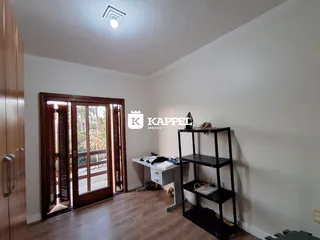 Uma sala de estar com piso de madeira e portas de vidro que dão acesso ao exterior.