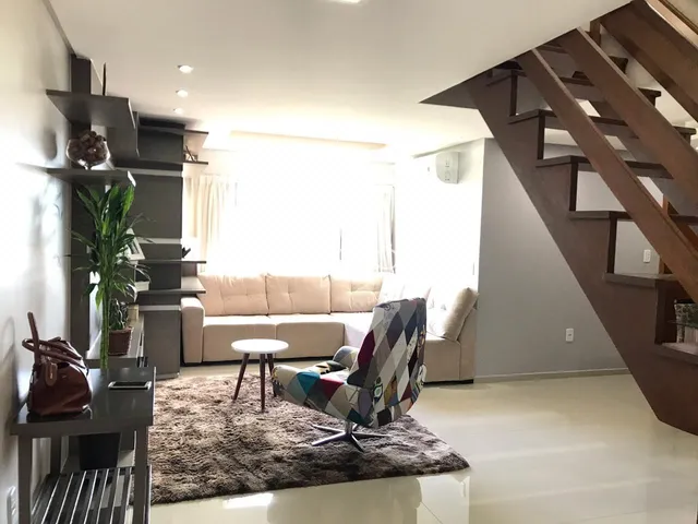 Sala de estar com sofá e escadaria em ambiente residencial.