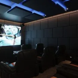 Foto de uma sala de estar com sofás escuros e teto com iluminação moderna.
