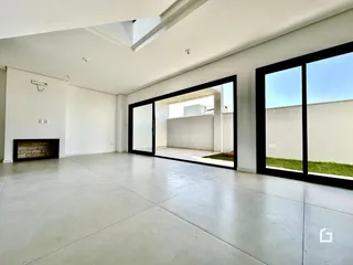 Sala de estar ampla com piso de concreto e portas de vidro que dão acesso ao exterior.