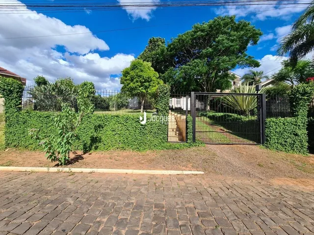 Vista da fachada de uma propriedade com cerca e vegetação.