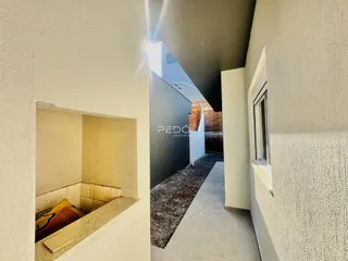 Vista de um corredor interno com paredes brancas texturizadas.