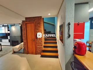 Hall de entrada com escadaria de madeira e porta de madeira.