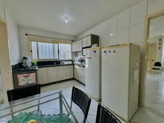 Imagem de uma cozinha com armários brancos e bancadas escuras em um imóvel no Brasil.
