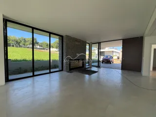 Sala de estar ampla com grandes janelas que oferecem vista para um campo verde.