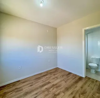 A sala apresenta piso de madeira clara e paredes brancas.