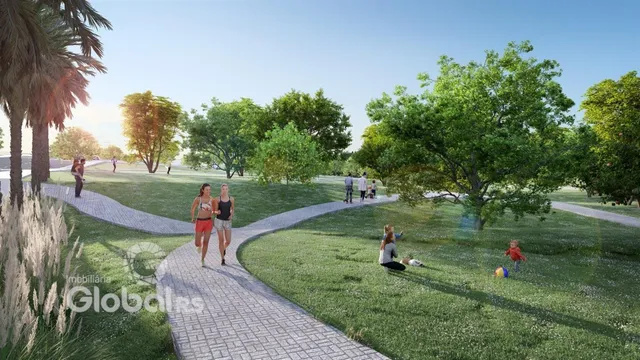 Caminho pavimentado atravessa um jardim verde com árvores ao fundo.