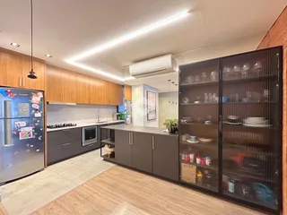Cozinha moderna com armários de madeira e estantes escuras.