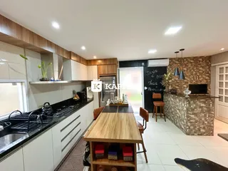 Cozinha moderna com armários brancos, bancadas escuras e ilha de madeira.