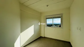 Interior de uma sala com paredes brancas e uma janela.
