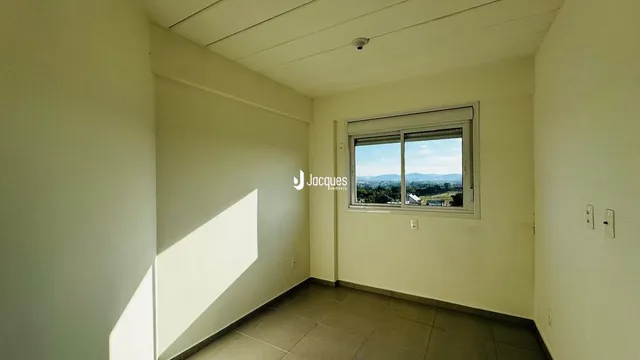 Interior de uma sala com paredes brancas e uma janela.
