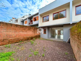 Fachada de um imóvel residencial com muro de tijolos e jardim na frente.