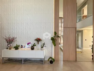 Parede branca com textura de losangos e um aparador branco na sala.