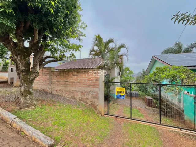 Vista externa de uma propriedade com muro de tijolos e cerca de metal.