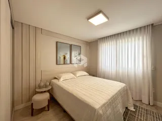 Quarto com cama de casal e cortinas brancas.
