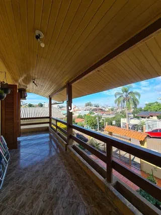 Corredor com teto inclinado e vista para o exterior de uma residência em Lajeado.