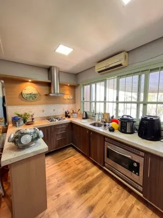 Uma cozinha com armários de madeira e piso de madeira é visível na imagem.