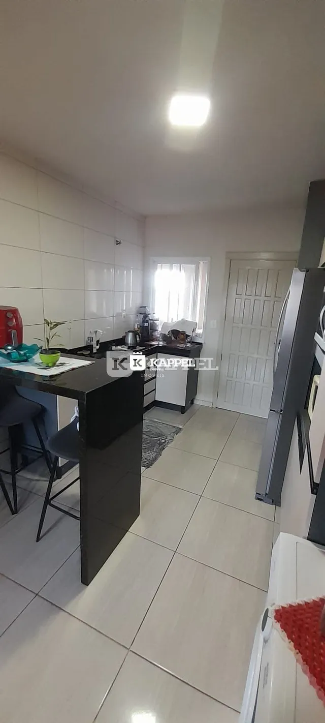 Cozinha com bancada escura e piso de cerâmica.