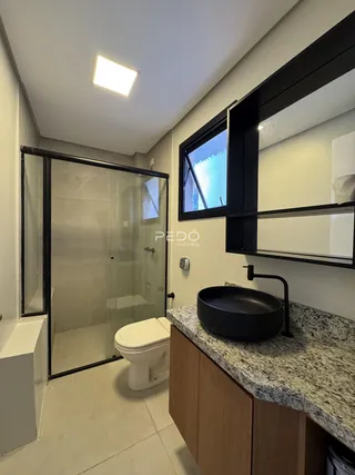 Foto de um banheiro com box de vidro e bancada moderna.