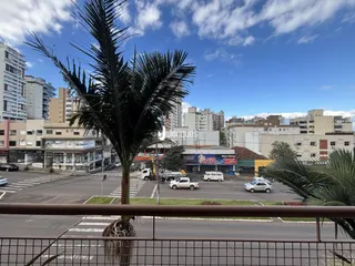 Vista externa de uma rua com árvores e edifícios no fundo.