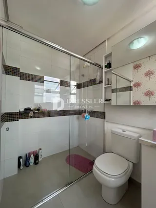 Foto de um banheiro com revestimento cerâmico e divisória de vidro.