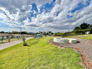 Vista externa do terreno com gramado e área de terra.