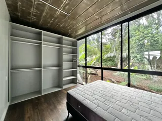 Quarto com grandes janelas e estantes embutidas na parede.