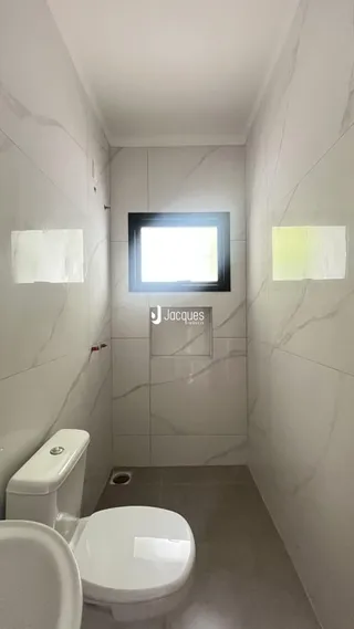Interior de um banheiro com paredes brancas e piso claro.