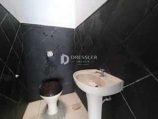 Foto de um banheiro com revestimento de azulejos escuros e piso claro.