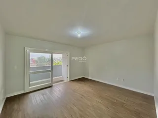 Ambiente interno de uma sala com piso de madeira clara e porta de vidro.