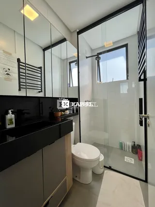 Banheiro moderno com box de vidro e bancada escura.