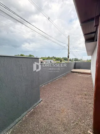 Vista externa de um pátio com muro e área de terra batida.