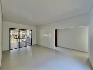 Ambiente interno de uma sala ampla com piso de cerâmica e portas de vidro.